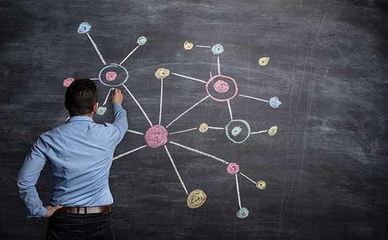 Businessman drawing a multicoloured network on blackboard