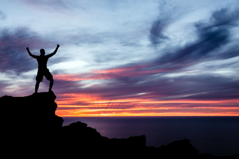 Man hiking silhouette in mountains, ocean and sunset