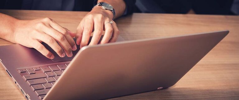 Hands typing on a laptop computer