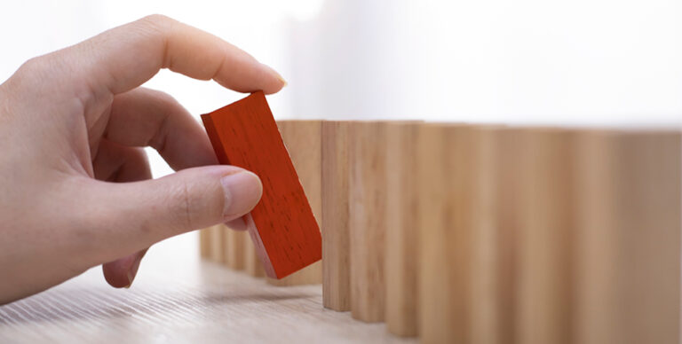 Person placing a red, wooden block - Customer Communications: Removing the Risk