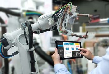 Engineer hand using tablet, heavy automation robot arm machine in smart factory industrial with tablet real time monitoring system application. Industry 4th iot concept.